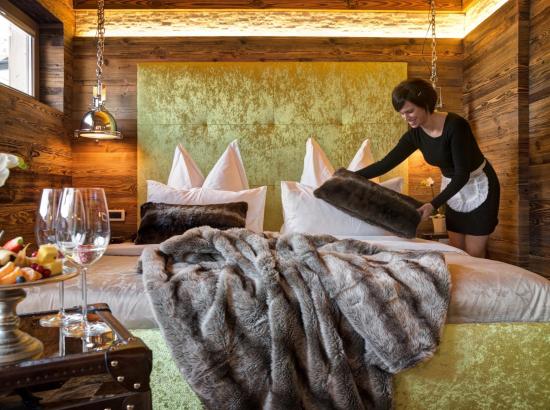 Ein Zimmermädchen macht das Bett im Chalet Design Alpin