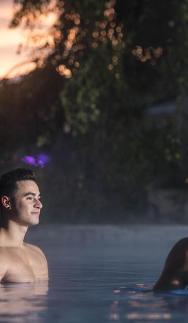 Due uomini si rilassano nella piscina all'aperto di sera.
