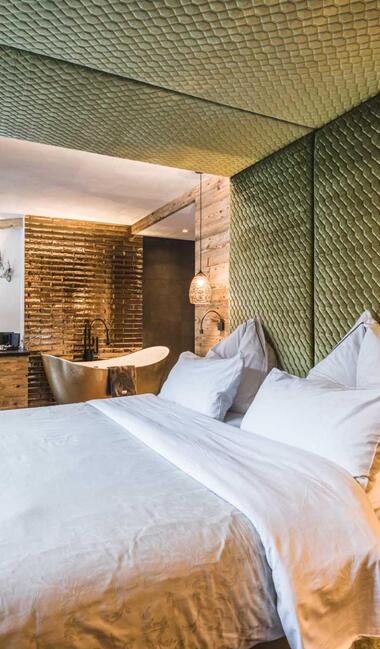 Love Suite im Hotel Alpin Garden mit Doppelbett, freistehender Badewanne und Holzelementen.